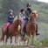 A small group of horseback riders smile as they stand amid lush vegetation